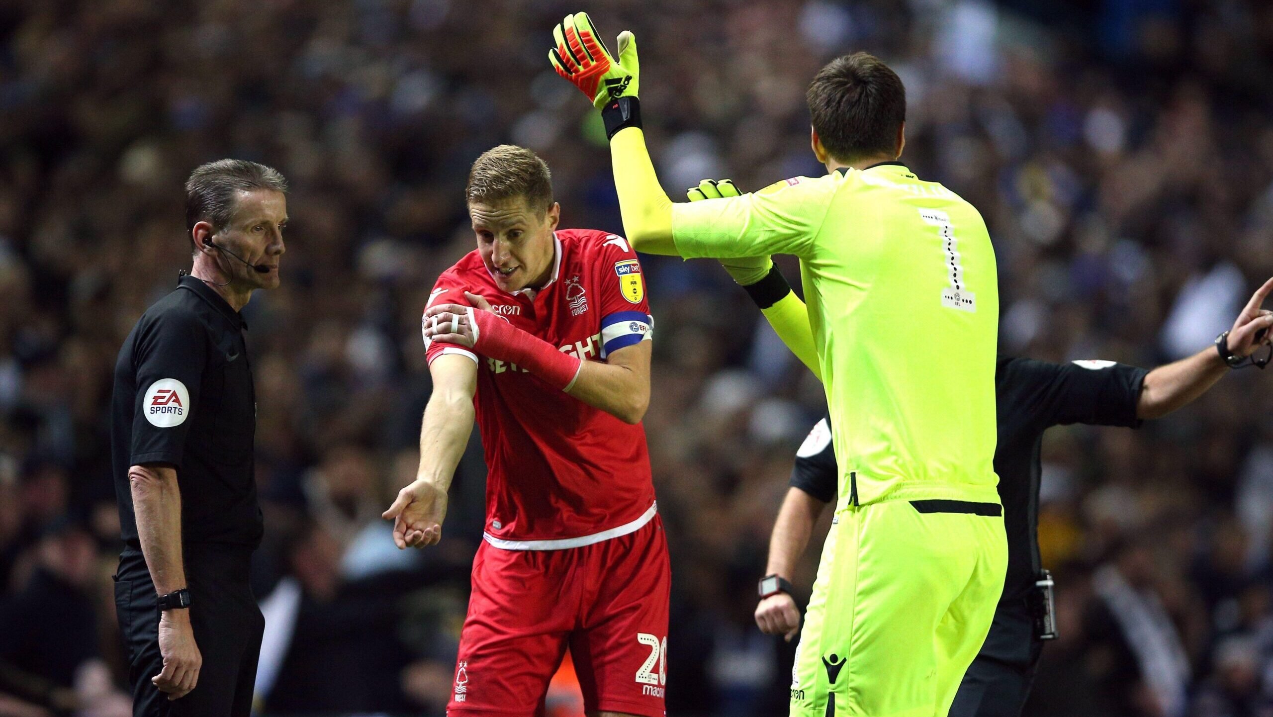 Nottingham Forest defender Michael Dawson gestures to the linesman that Kemar Roofe handled the ball into their goal, with big freak goalkeeper Costel Pantilimon mimicking him. Neither are separated from the lino by plexiglass.