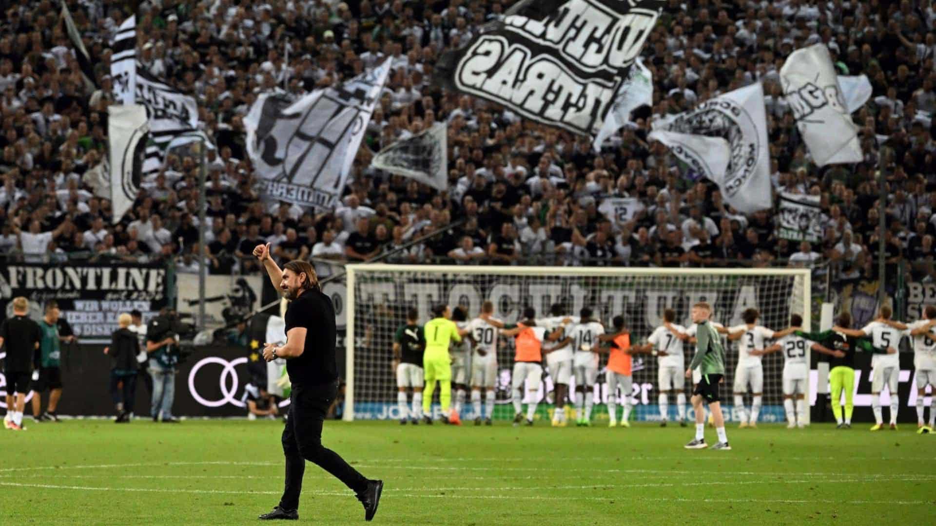 Daniel Farke walks across the pitch after a Borussia Monchengladbach win last season, with his team in the background saluting one of those really cool German stands full of fans with flags and beer