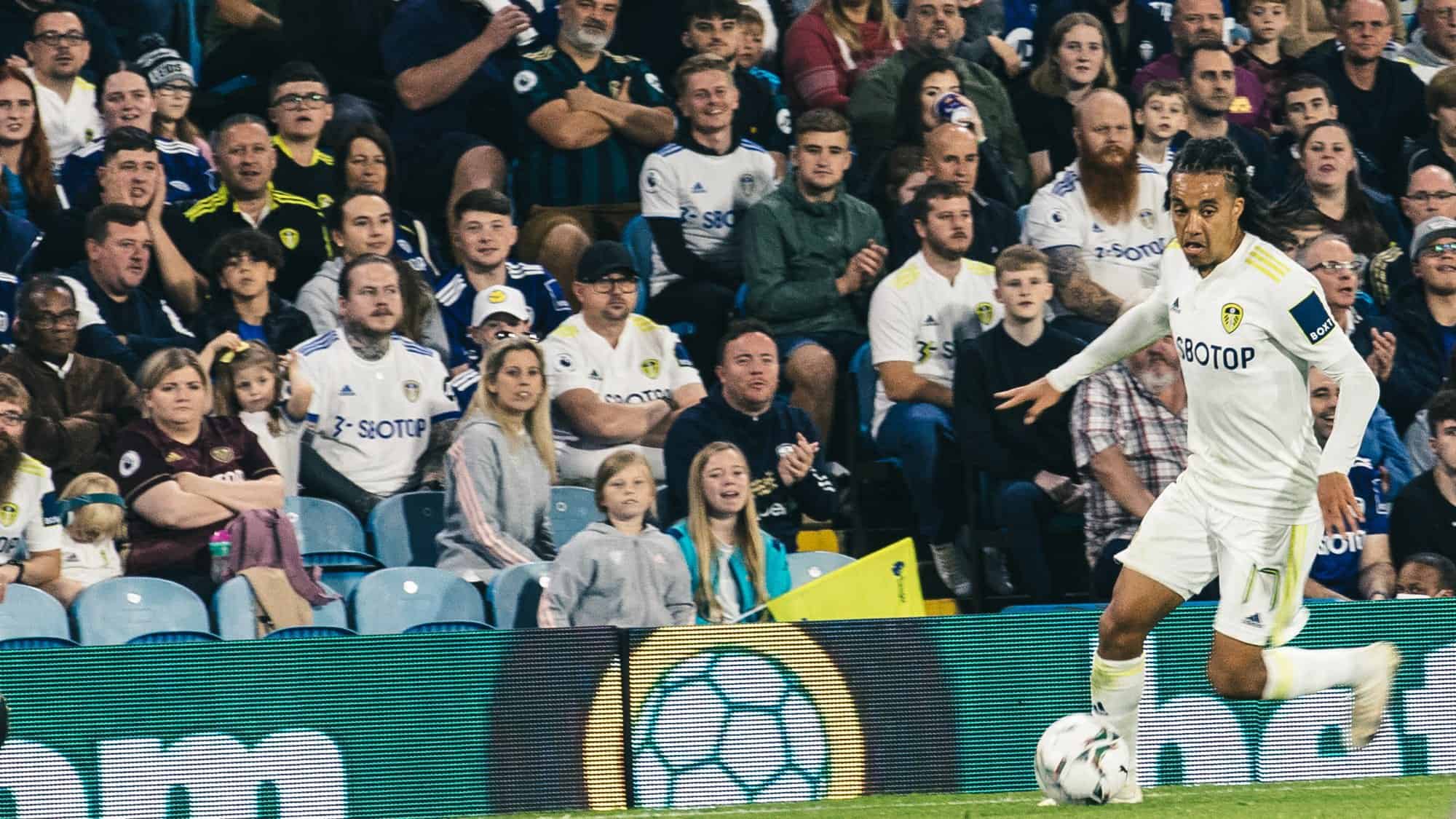 Helder Costa is running with the ball in front of crowds in Elland Road's East Stand