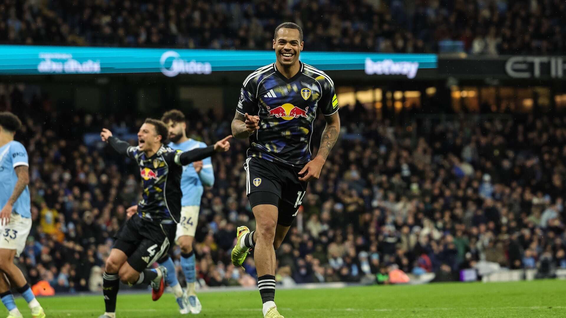 Lukas Nmecha runs off celebrating his equaliser at Man City with Ethan Ampadu still following the rebound, arms aloft, all the way to the away end