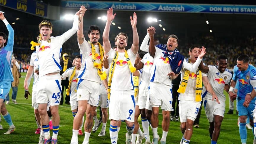 Pat Bamford, Pascal Struijk, Joel Piroe and Harry Gray with their arms in the air saluting the crowd. Piroe's got a flag over him and his eyes are shut, obviously