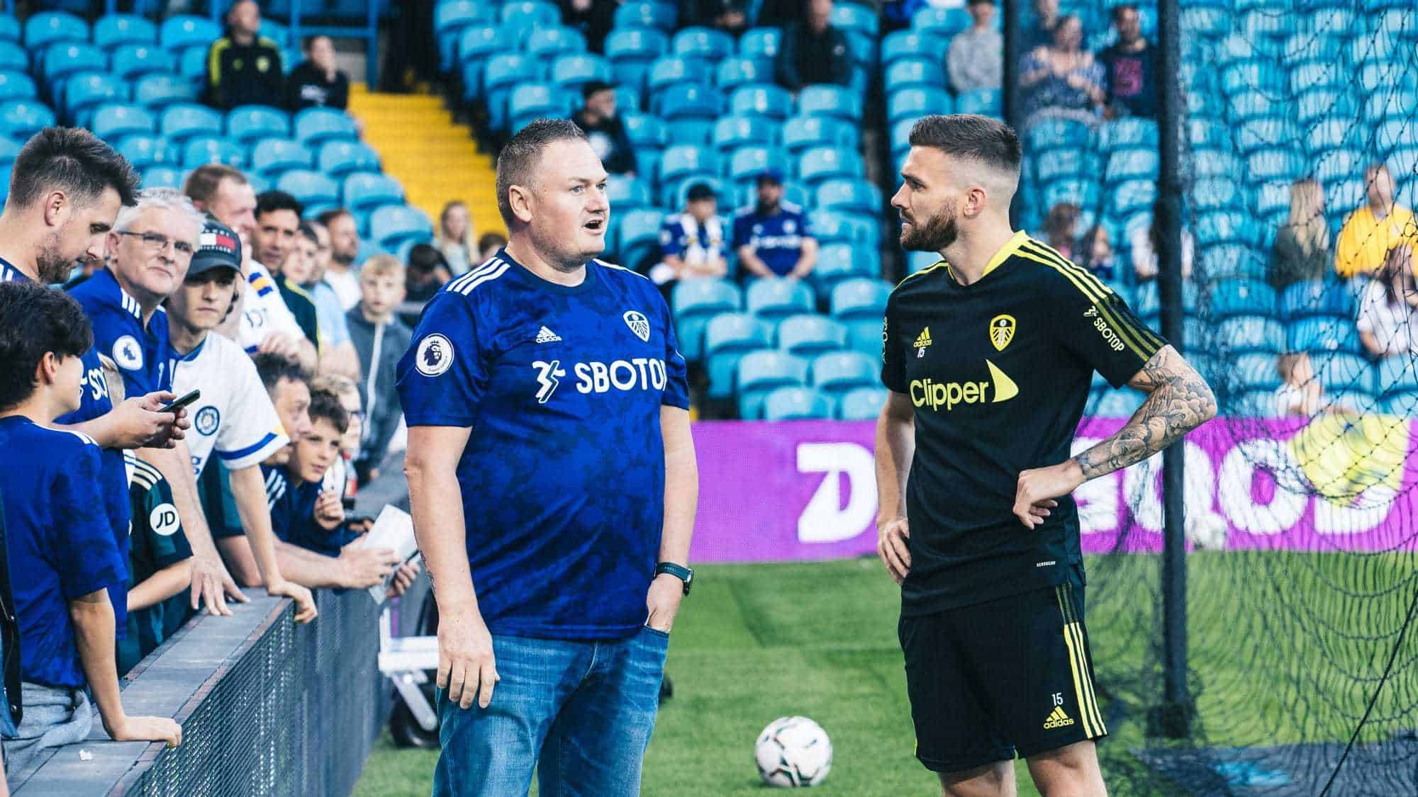 Stuart Dallas is talking to a fan by the side of the pitch before the Crewe game