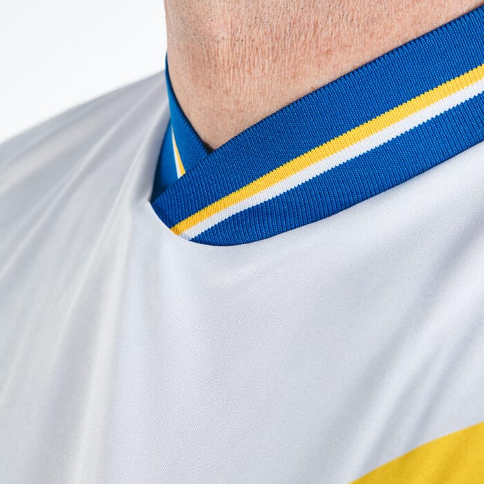 A close up view of the collar of our TSB x Admiral 2024 home shirt, blue with a yellow and white band on an all-white shirt