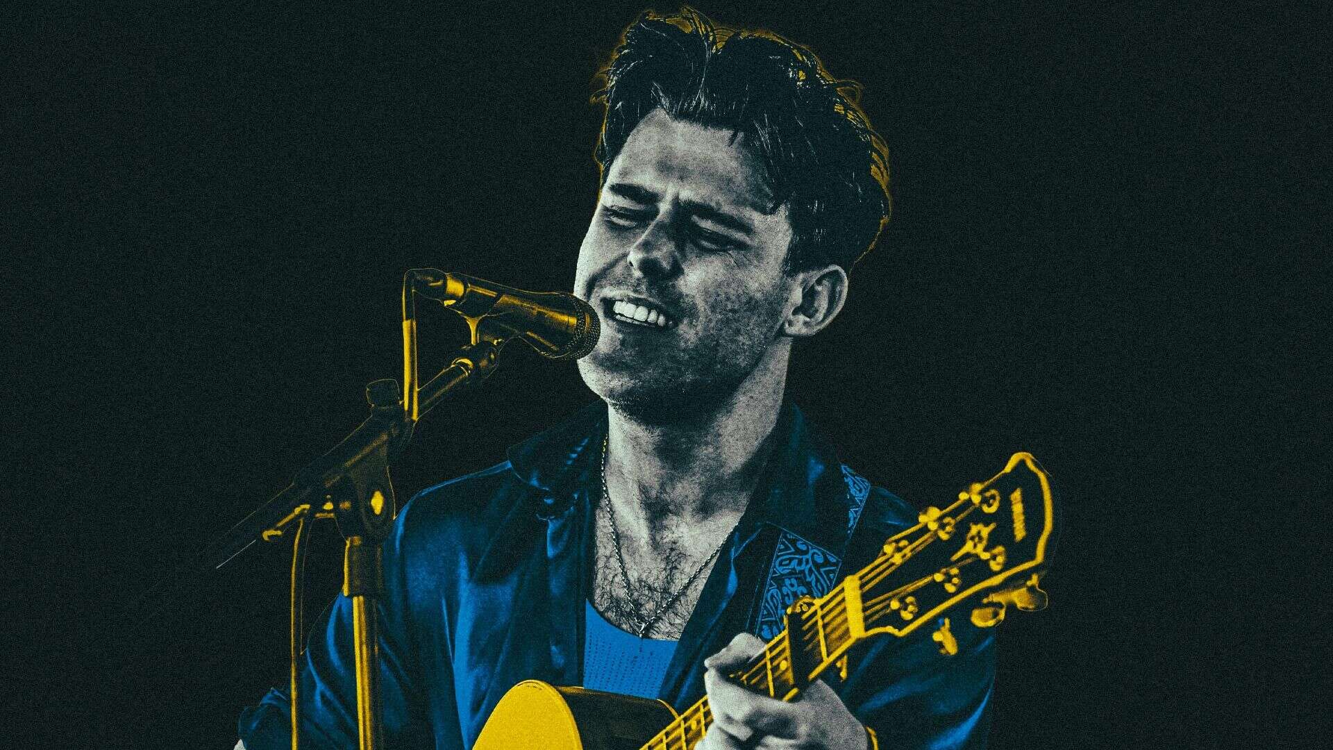 Actor, musician and Leeds fan Niall McNamee performing live on stage singing and playing an acoustic guitar